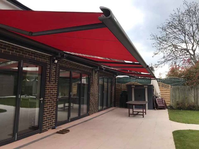 red awning over a patio area adjoining a large kitchen-diner extension