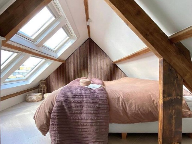a sustainable loft conversion with timber beams, wood panelling and neutral decor