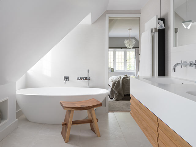 En-suite bathroom ideas: freestanding tub under skylight in sloping ceiling with double vanity unit, white walls and wooden features