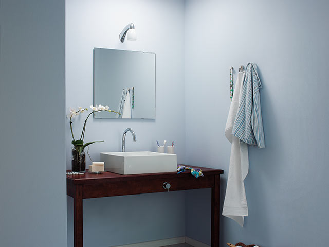 En suite bathroom in powder blue with white square basin resting on wooden side board
