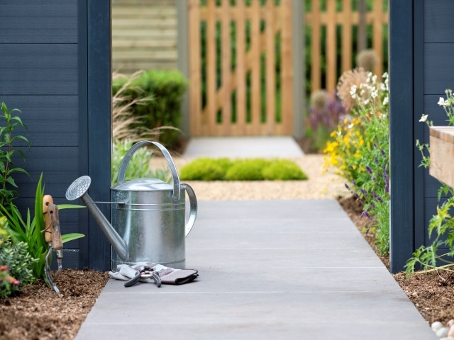 modern garden with grey stone slabs and dark navy painted partition