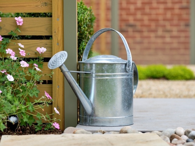 steel watering can next to a steel fence post