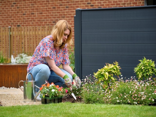 woman gardening next to a modern grey-painted low fence
