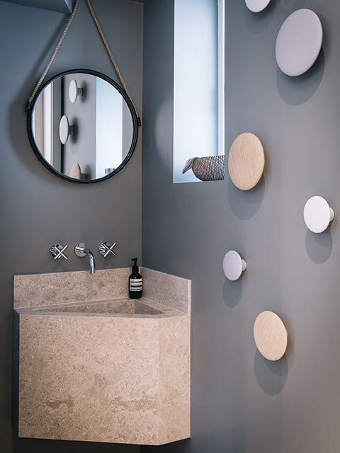 Corner basin in marble on grey wall of en suite bathroom
