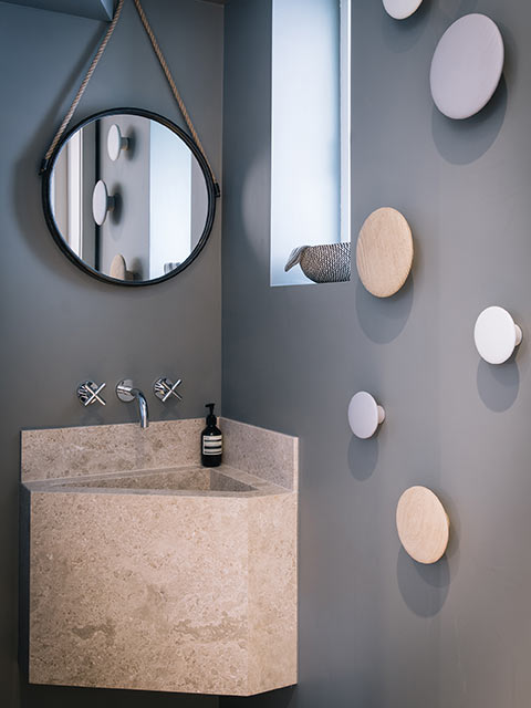 Corner basin in marble on grey wall of small cloakroom