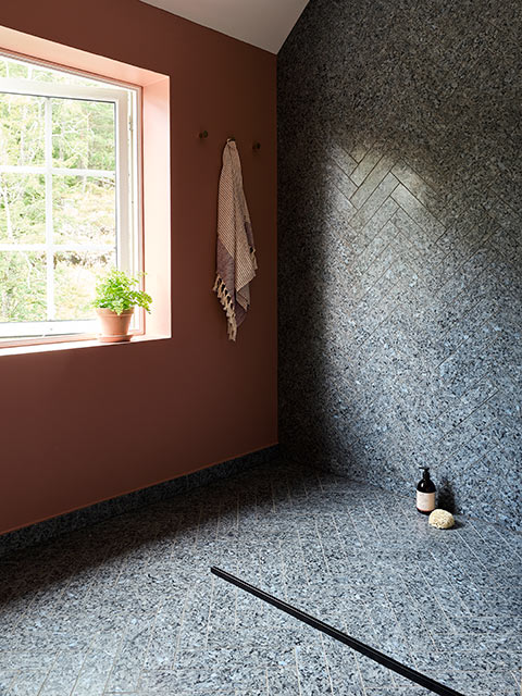 En suite bathroom with dark stone wall and flooring and large window