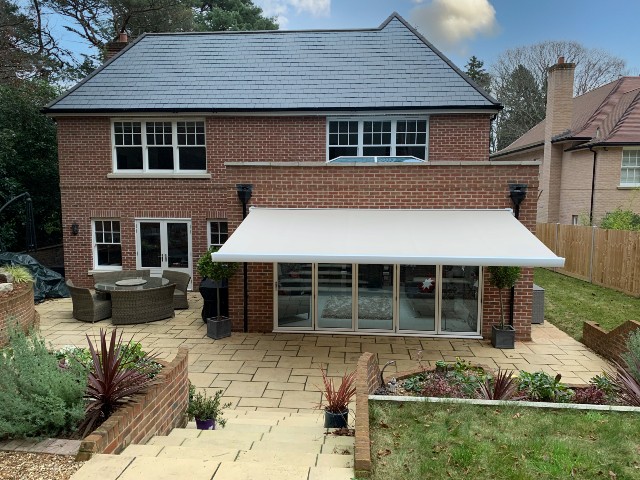 large patio awning on a kitchen extension in a detached red-brick house