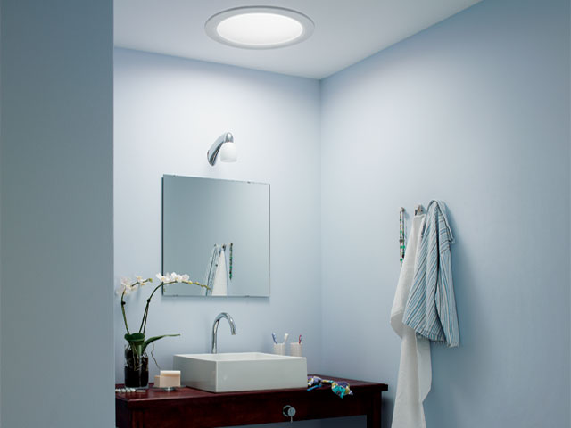 sun tunnel in an en-suite bathroom with powder blue walls and white square basin resting on wooden side board 