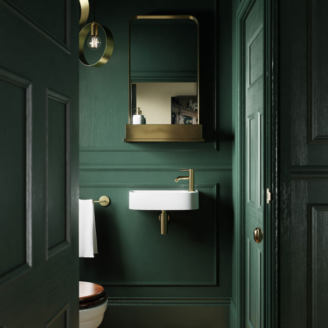dark green bathroom with burnished brass mirror and fixtures
