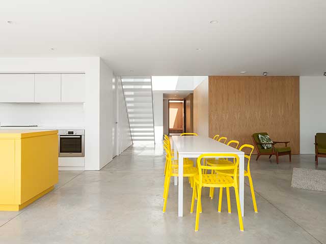 white concrete flooring in an open-plan kitchen-diner with yellow furniture