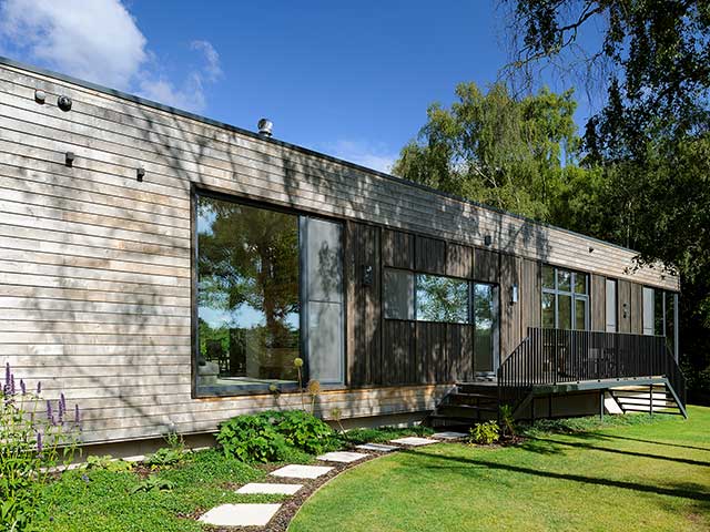 A timber-clad prefab home elevated above ground in the New Forest