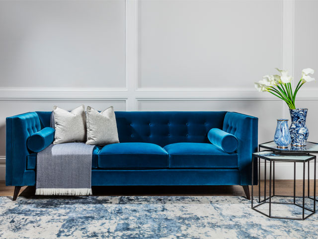 blue velvet sofa in white room with a blue and white rug