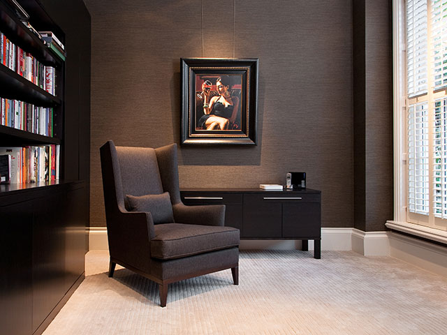 Hotel-style reading nook with dark walls, dark furnishings and a big window