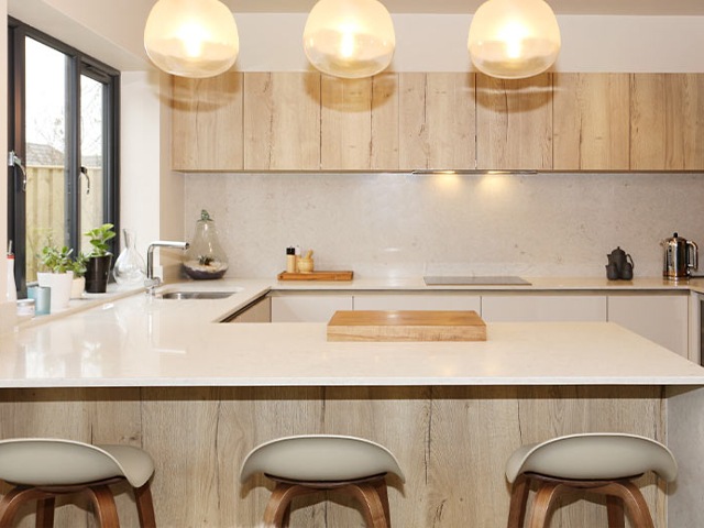 u-shaped kitchen with globe pendants, wooden cabinets and white gloss worktops