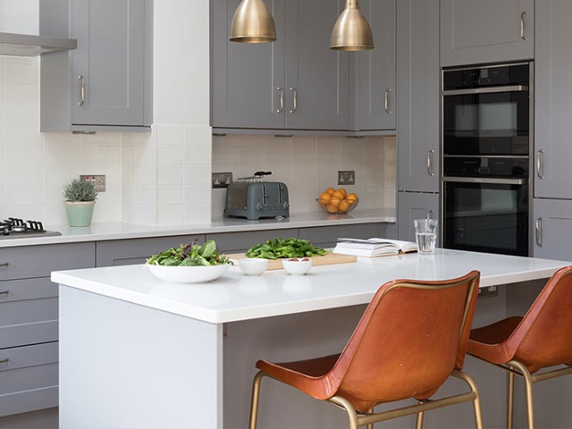 small kitchen island with white worktop and overhang breakfast with tan bar stools