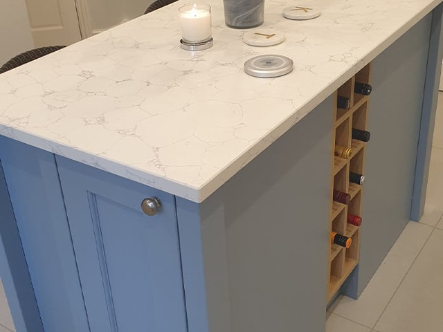 integrated wine storage in blue grey cabinets with marble worktop