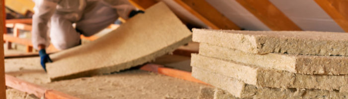 man fitting loft insulation in PPI with face mask