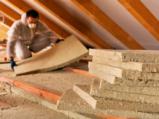 man fitting loft insulation in PPI with face mask