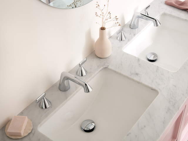 contemporary chrome bathroom brassware on a marble worktop with pink cabinets