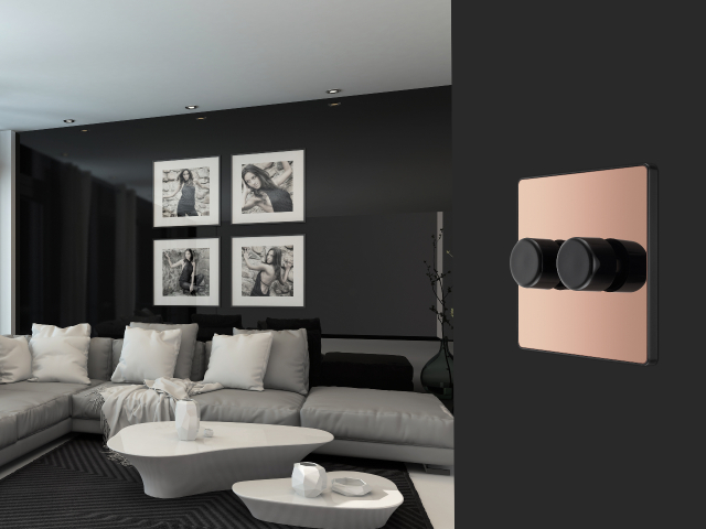 Rose gold smart dimmer switch with black knobs on a black wall