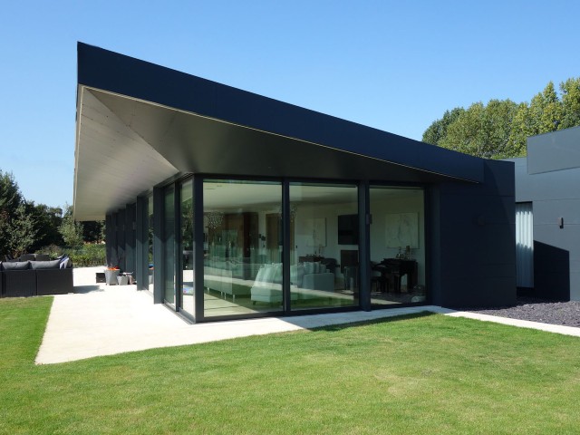 a contemporary rural home with floor-to-ceiling glass, solar shading and black cladding