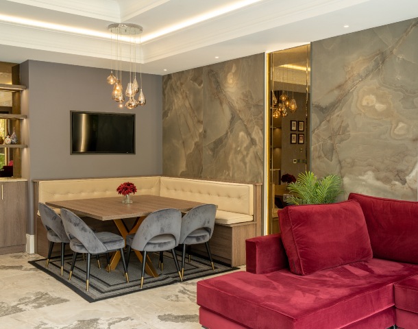 luxury stone walls and flooring in high-end home with wine-coloured sofa and corner dining table