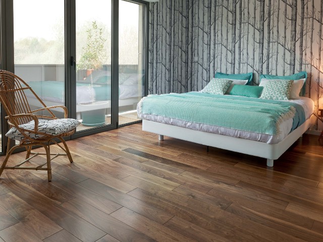 bedroom with floor to ceiling windows, monochrome forest print wallpaper, wooden floor and balcony