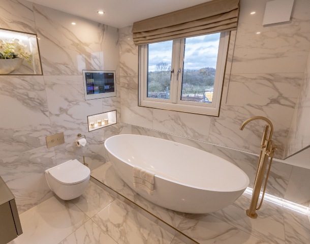 large format marble tiles in a luxury bathroom with freestanding oval bath and gold tap