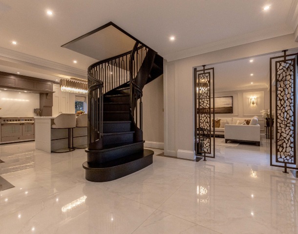 large format tiles in an open-plan hallway and kitchen with winding dark-wood staircase