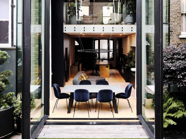 Steel framed glass pivot doors leading from open-plan kitchen-diner to patio terrace