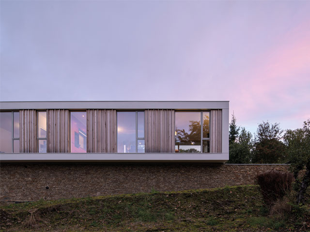 house designs for sloping sites: this house in Northumberland, looks like it’s balanced on a rubble-stone wall with lower level tapering to meet the slope