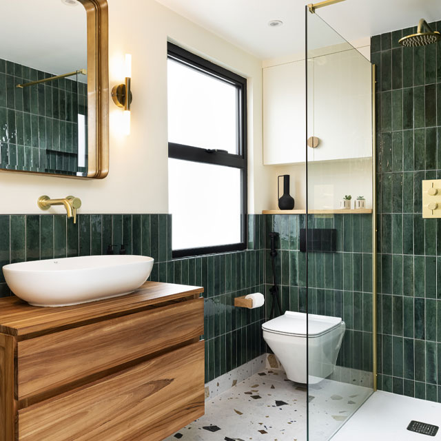 loft extension wet room with green tiles, gold finishings and natural wood cabinets
