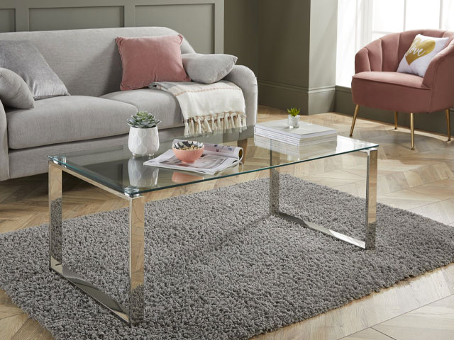Furniturebox glass and chrome table in living room with grey sofa and pink accent chair