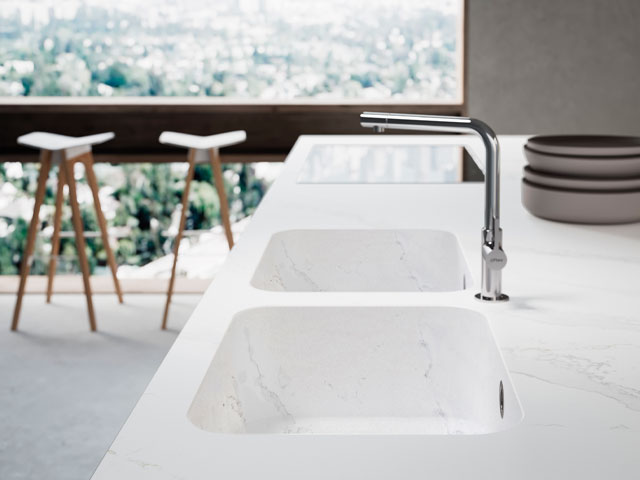 Integrated kitchen sink in white composite worksurface in modern apartment