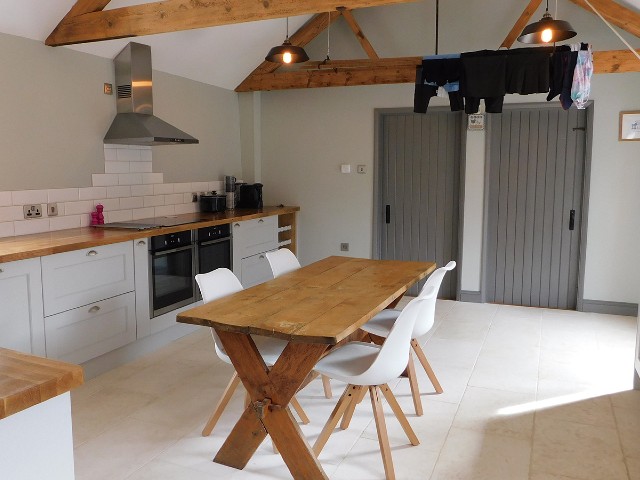 country kitchen with vaulted, wooden-beamed ceiling, wooden dining table and wooden worktops 