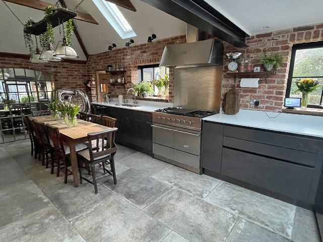 kitchen without wall cabinets showcasing exposed bricks, large range cooker and deep storage drawers in grey