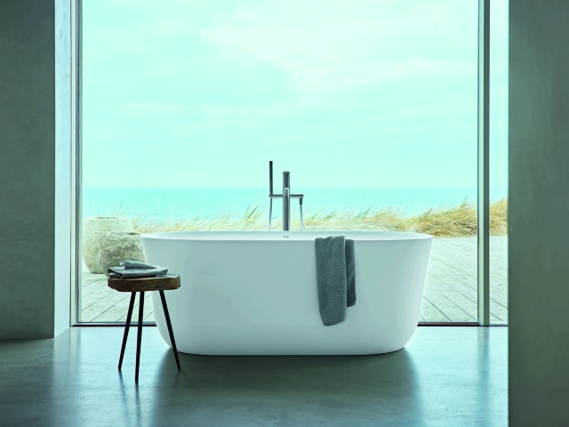 Philippe Starck freestanding bath in front of a floor-to-ceiling window overlooking a private terrace and beach