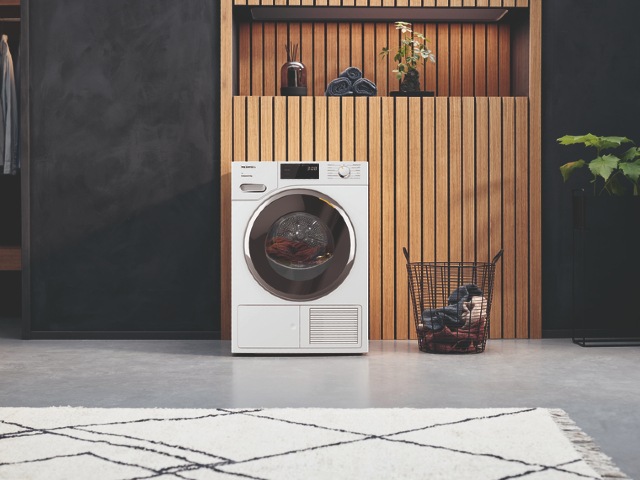 quiet tumble dryer in a large kitchen utility with black walls and wooden panels