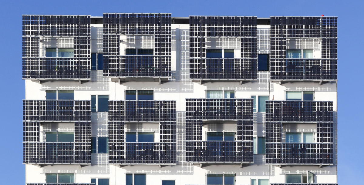 Contrasting black solar sells surround multiple balconies on a white building