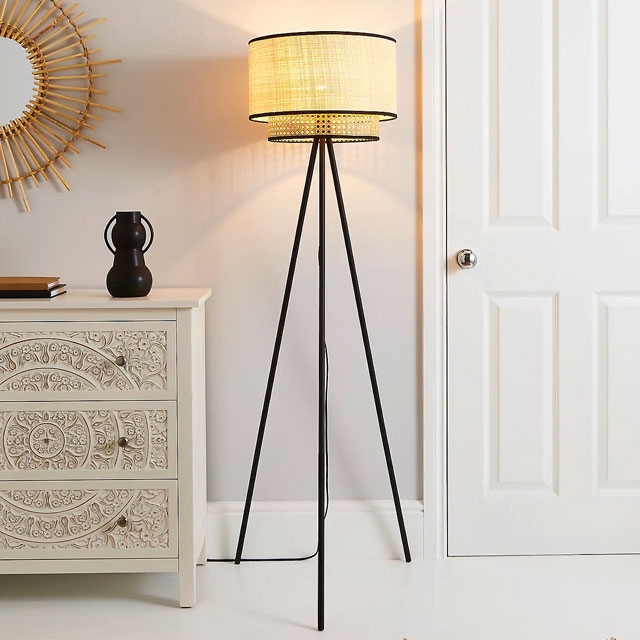 tripod floor lamp with black legs and rattan-effect lampshade in a white room