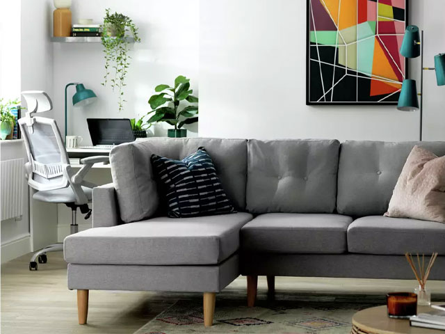 Scandi-style grey corner sofa with tapered wooden legs in a live-work space in a small flat