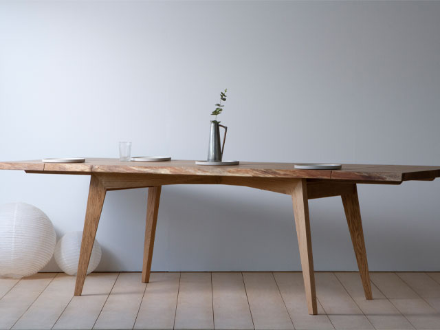 extending oak dining table table against a white wall with natural wooden floor boards