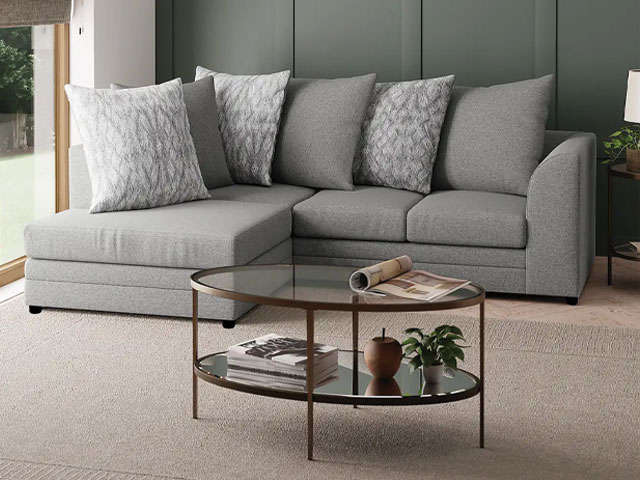 grey corner sofa with scatterback cushions in a small living room with glass coffee table