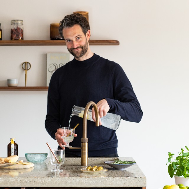 man pouring sparkling water from a Quooker CUBE tap system at home 