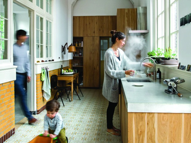 Woman pouring hot water from an instant boiling water tap in a family kitchen