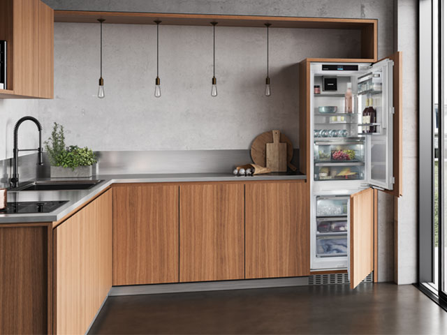 Quiet integrated fridge-freezer in a modern kitchen with grey walls and natural wooden cabinets 