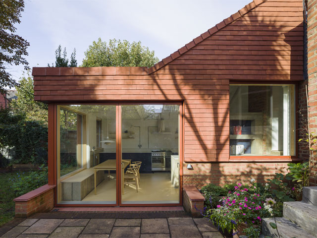 steel frame addition with concrete blockwork and a red tile-clad exterior spanning the width of a flat and the side return 