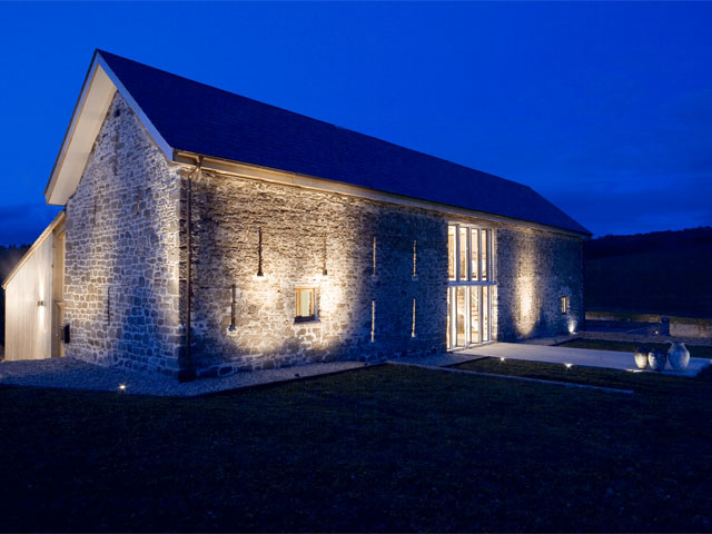 Stone barn conversion exterior at dusk up lighting 