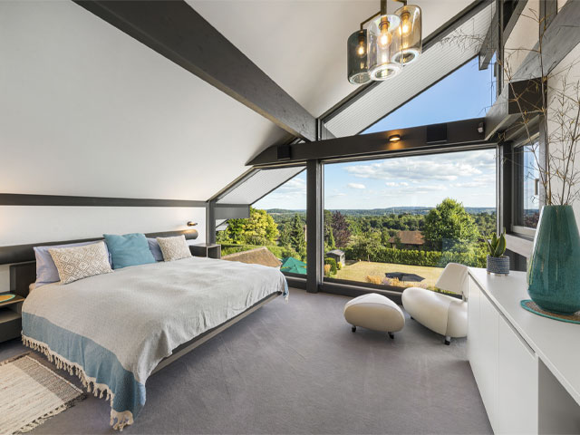 bedroom with pitched roof and double-height windows by Huf Haus