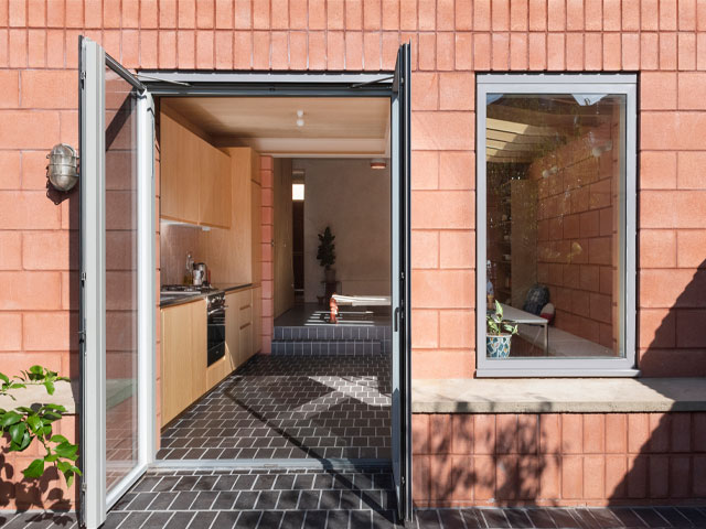 rear extension with kitchen and dining area that uses the same brick inside and out, plus a tiled floor that runs from the indoors out to the patio 
